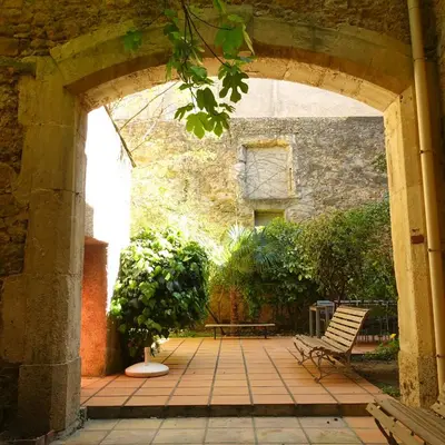 an archway with a bench and a tree in a courtyard at GîTE-FAMILLE NOMBREUSE-SÉMINAIRE-PATIO in Ornaisons