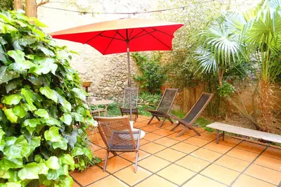 a patio with a red umbrella and chairs and a bench at GîTE-FAMILLE NOMBREUSE-SÉMINAIRE-PATIO in Ornaisons