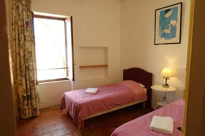 a small room with two beds and a window at GîTE-FAMILLE NOMBREUSE-SÉMINAIRE-PATIO in Ornaisons