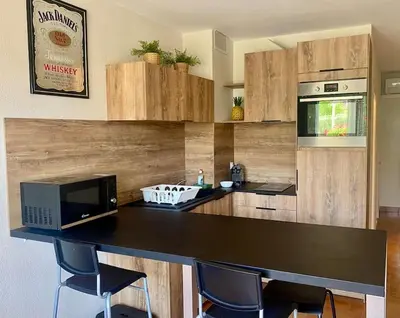 a kitchen with a counter with chairs and a microwave at Beau T3 - plain pied - terrasses in Port-la-Nouvelle