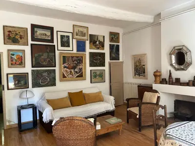 a living room with a couch and many pictures on the wall at Chez Elise - Gîte de charme - Abbaye de Fontfroide in Bizanet