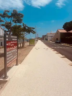 a sidewalk with a sign on the side of a road at Le studio du Port in Port-la-Nouvelle