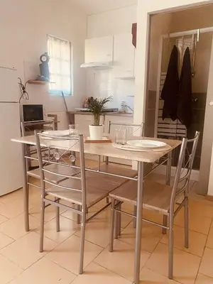 a dining room table with two chairs and a kitchen at Le studio du Port in Port-la-Nouvelle
