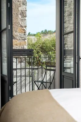 a room with a balcony with two chairs and a window at Bouquerie Lagrasse in Lagrasse