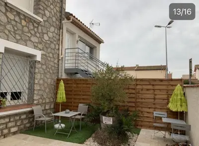 a patio with chairs and tables in front of a fence at LA MADDYSON in Narbonne