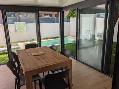 a dining room with a table and chairs and a pool at Petite Bulle in Narbonne