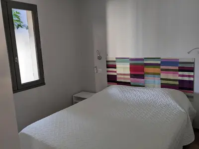 a bedroom with a white bed with a colorful headboard at Petite Bulle in Narbonne