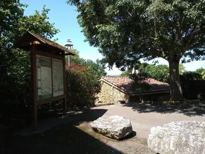 a sign in a park with a tree and a building at Au Repos in Tréziers