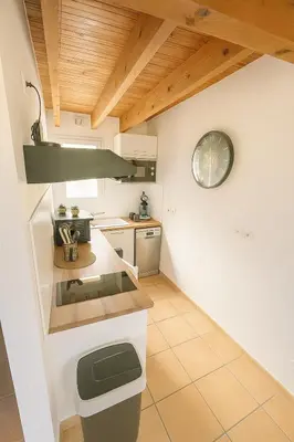a kitchen with a counter and a clock on the wall at Appartement près du canal du midi in Mirepeisset