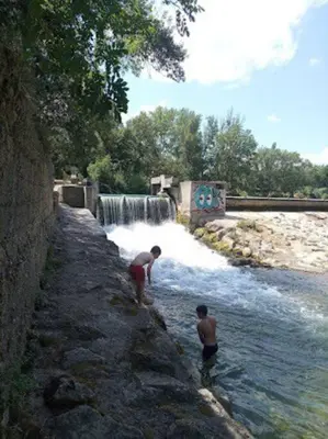 two men standing in the water near a waterfall at Appartement près du canal du midi in Mirepeisset