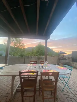 a table and chairs on a patio with a view at Ferme-auberge le cochon du Madres in Escouloubre