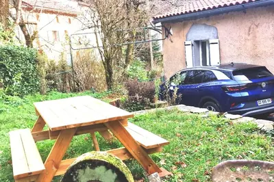 a wooden picnic table in a yard with a car at Maison au calme avec jardin et parking privé in Rouairoux