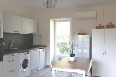 a kitchen with a table and a white refrigerator at Maison au calme avec jardin et parking privé in Rouairoux
