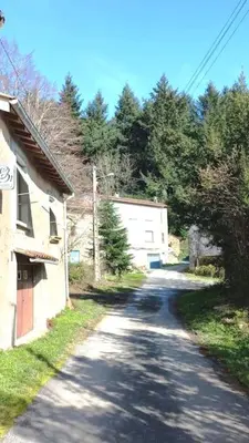 an empty road with a building and trees on the side at Maison au calme avec jardin et parking privé in Rouairoux
