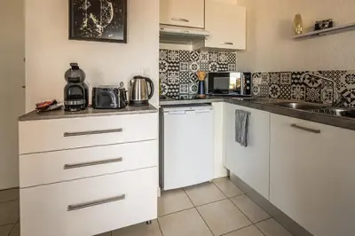 a small kitchen with white cabinets and appliances at Appartement 