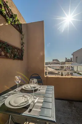 a table with plates and wine glasses on a balcony at Appartement 