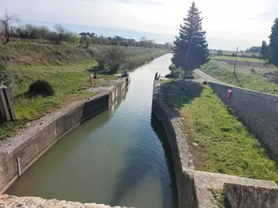 a canal in a field with people walking in the water at Studio confortable et calme au millieu des vignes in Moussan
