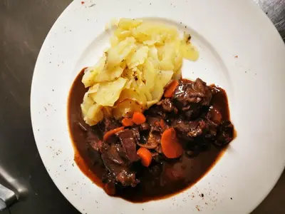 a white plate of food with meat and potatoes at Le Laurenti in Quérigut