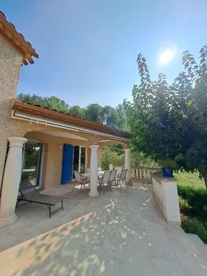 a patio with chairs and tables in front of a house at Belle villa entre garrigue et rivière in Saint-Chinian