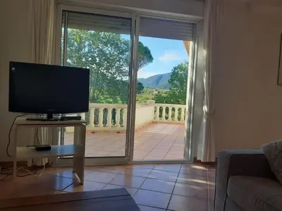 a living room with a television and a sliding glass door at Belle villa entre garrigue et rivière in Saint-Chinian