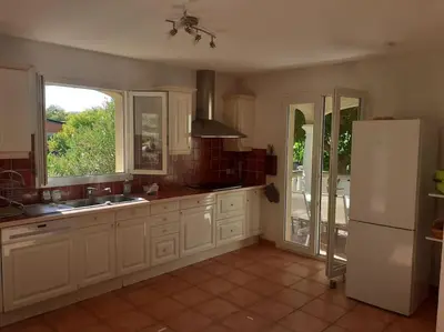 a kitchen with white cabinets and a white refrigerator at Belle villa entre garrigue et rivière in Saint-Chinian