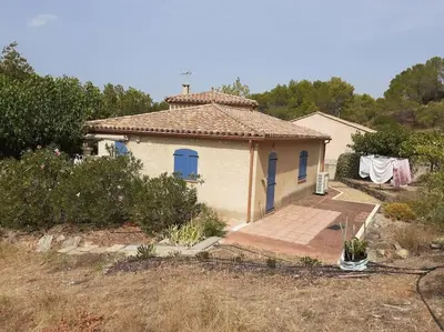 a small white house with blue windows and a yard at Belle villa entre garrigue et rivière in Saint-Chinian