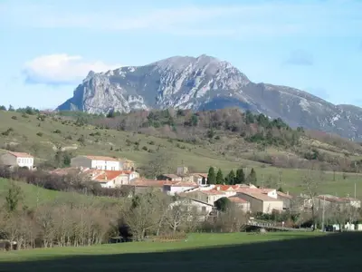a town in a field with a mountain in the background at Gite de l'école in Saint-Louis-et-Parahou