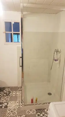 a shower with a glass door in a bathroom at Gite de l'école in Saint-Louis-et-Parahou