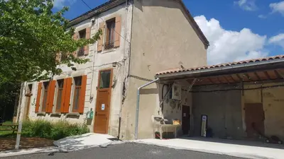 an old building with orange doors and a garage at Gite de l'école in Saint-Louis-et-Parahou