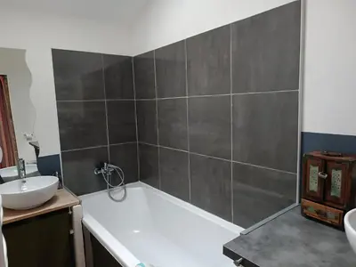 a bathroom with a bath tub and a sink at Charmante maison village QUERIGUT in Quérigut