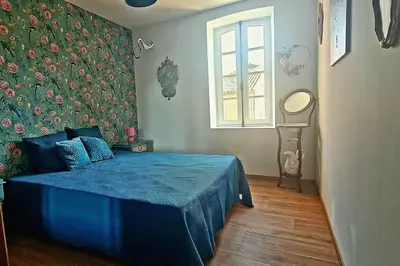 a bedroom with a blue bed with a floral wall at Domaine VILLECARLA Gîte 1, Canal du Midi Carcassonne in Villedubert