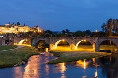 a bridge over a river with a city in the background at Domaine VILLECARLA Gîte 1, Canal du Midi Carcassonne in Villedubert