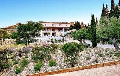 a garden with trees and plants in front of a building at Cozy Home In Stjean-De-Minervois in Saint-Jean-de-Minervois