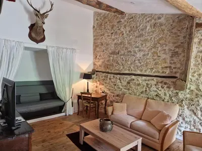 a living room with a couch and a stone wall at Le Grand Cerf - 4 Couchages in Nalzen