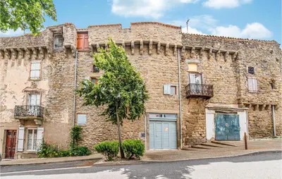 an old stone building with a tree in front of it at Awesome Home In Peyriac-Minervois in Peyriac-Minervois