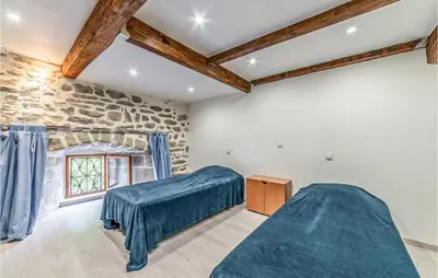 a bedroom with two beds and a stone wall at Awesome Home In Peyriac-Minervois in Peyriac-Minervois