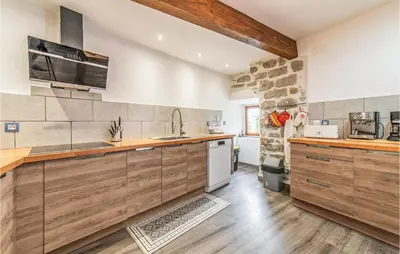 a kitchen with wooden cabinets and a stone wall at Awesome Home In Peyriac-Minervois in Peyriac-Minervois