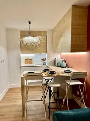 a kitchen with a table and stools in a room at Le Quai Secret d'Augustine centre &vue canal avec draps serviettes et ménage in Narbonne