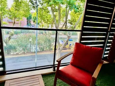 a red chair sitting in front of a window at Le Quai Secret d'Augustine centre &vue canal avec draps serviettes et ménage in Narbonne