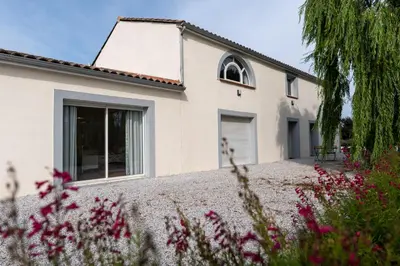 a white house with flowers in front of it at Chez PhiL in La Pomarède
