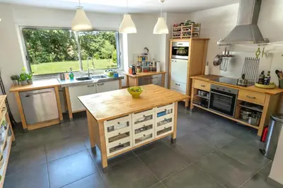 a kitchen with a wooden island in the middle at Chez PhiL in La Pomarède