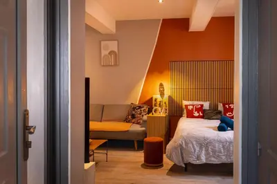 a bedroom with orange walls and a bed and a chair at Le Limouxin jungle Wifi, petit balcon *Oc Keys in Limoux