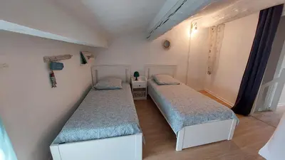 two twin beds in a small room with at Charmante maison au village in Gruissan