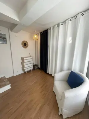 a living room with a white chair and curtains at Charmante maison au village in Gruissan