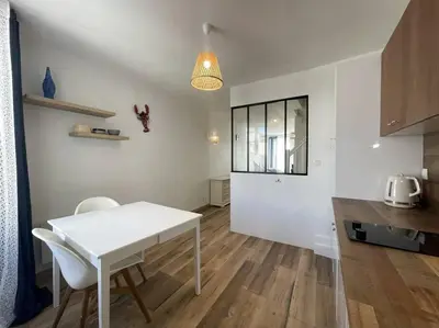 a white kitchen with a table and chairs in a room at Charmante maison au village in Gruissan