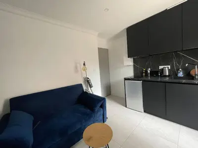 a living room with a blue couch and a kitchen at Appt 1 chambre jardin parking in Narbonne