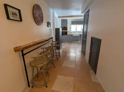 a room with a bar with stools and a clock on the wall at Maison Porte Saint Croix in Bize-Minervois