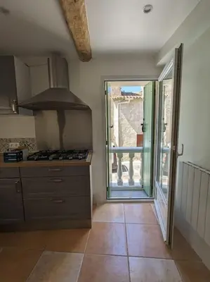 a kitchen with a stove and a door to a patio at Maison Porte Saint Croix in Bize-Minervois