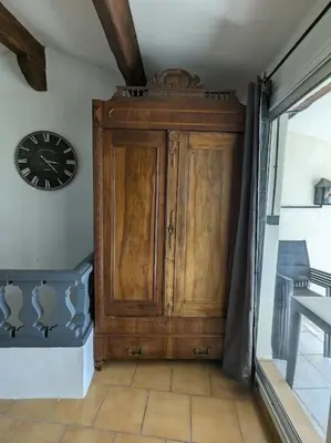 a wooden cabinet in a room with a clock on the wall at Maison Porte Saint Croix in Bize-Minervois