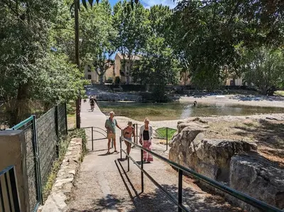 a group of people standing on a walkway near a pond at Maison Porte Saint Croix in Bize-Minervois
